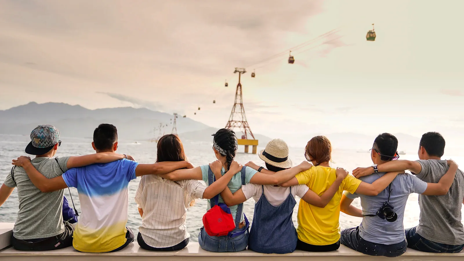 Group of friends sitting arm in arm by the sea